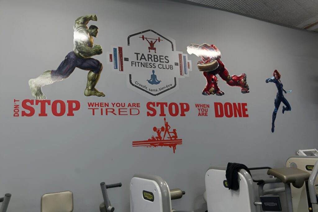 Mur de gym Tarbes Fitness Club: Hulk en fente, Iron Man, Black Widow, logo Crossfit, et le mantra 'DON'T STOP WHEN YOU ARE TIRED STOP WHEN YOU ARE DONE'.